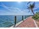 Picturesque waterfront view from a brick-paved walkway, complemented by palm trees and a serene ocean backdrop at 26950 Pavin Dr, Englewood, FL 34223