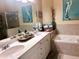 Bright bathroom with a double sink vanity, tub, tiled surround, and decor at 3363 Grand Vista Ct # 203, Port Charlotte, FL 33953