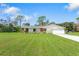 Single-story home with green roof, white exterior, and spacious lawn at 1115 Larchmont Dr, Englewood, FL 34223