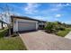 Brick paver driveway leads to a modern home with gray garage door and landscaped yard at 1337 Sorrell Way, North Port, FL 34289
