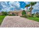 Home with paver driveway, two-car garage, and tropical landscaping at 13104 Creekside Ln, Port Charlotte, FL 33953