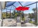 Screened patio with lounge chairs and red umbrella at 15764 Autry Cir, Port Charlotte, FL 33981