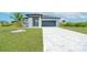 White house with gray roof, black garage door, and paved driveway at 384 Baytree Dr, Rotonda West, FL 33947