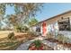 Charming house with a landscaped front yard, featuring a red door and mature tree at 700 Coquina Ct, Nokomis, FL 34275