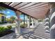 A shaded walkway with a wooden pergola and stone columns, overlooking a resort-style pool at 13215 Amerigo Ln, Venice, FL 34293