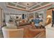 Living room with coffered ceiling, leather sofa, and access to kitchen at 13215 Amerigo Ln, Venice, FL 34293