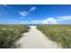 Scenic sandy path leads to a sunny beach with blue skies and scattered beachgoers at 2255 N Beach Rd # 9, Englewood, FL 34223