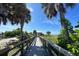 Picturesque wooden walkway leading to the beach, framed by palm trees and lush greenery at 2255 N Beach Rd # 9, Englewood, FL 34223