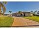 Tan three-car garage house with a paved driveway and palm trees at 2 Marker Rd, Rotonda West, FL 33947