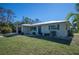 Single-story home with metal roof, a blue door and landscaped yard at 445 Stewart St, Englewood, FL 34223