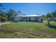 Newly renovated home with metal roof, blue door and green landscaping at 445 Stewart St, Englewood, FL 34223