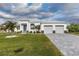 Charming home featuring a two-car garage, paver driveway, manicured lawn, and tropical landscaping at 8198 Clyde Cir, Port Charlotte, FL 33981