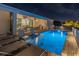 Night view of an inviting backyard pool with sun loungers, outdoor kitchen and seating area at 8198 Clyde Cir, Port Charlotte, FL 33981