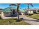 Tan house with a green metal roof, paver driveway, and palm trees at 9567 Honeymoon Dr, Port Charlotte, FL 33981