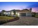 Beautiful two-story home with a three-car garage and a brick driveway at dusk at 385 Pelican Bnd, Placida, FL 33946