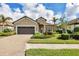 Tan house with brown garage door, blue front door, and landscaped yard at 26812 Pavin Dr, Englewood, FL 34223