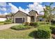 Tan house with brown garage door, blue front door, and landscaped yard at 26812 Pavin Dr, Englewood, FL 34223