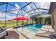 Relaxing screened-in pool with a red umbrella, waterfall feature, and expansive views at 26812 Pavin Dr, Englewood, FL 34223