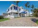 White two-story home with a blue awning and palm trees at 5850 Gasparilla Rd # M7, Boca Grande, FL 33921