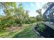 Landscaped backyard with mature trees and a natural path at 8527 Creekview Ln, Englewood, FL 34224