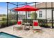 Poolside lounge chairs and red umbrella for shade at 26866 Weiskopf Dr, Englewood, FL 34223