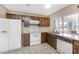 Kitchen with white appliances, wood cabinets, and view of sunroom at 7379 Rosemont Dr, Englewood, FL 34224