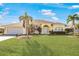 House exterior showcasing a yellow painted home with palm trees and a lush lawn at 738 Boundary Blvd, Rotonda West, FL 33947