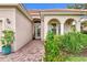 Front entrance with arched entryway, lush landscaping, and brick walkway at 13376 Creekside Ln, Port Charlotte, FL 33953