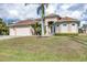 Tan house with three-car garage, palm trees, and landscaped lawn at 17164 Canary Ln, Port Charlotte, FL 33948