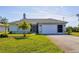 One-story home with attached garage,palm trees, and well-manicured lawn at 185 Cougar Way, Rotonda West, FL 33947