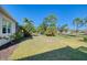 Landscaped backyard showcasing a home with a screened patio and lush greenery at 21228 Sandal Foot Dr, Venice, FL 34293