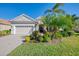 House with a beige facade, two-car garage, and lush landscaping at 21228 Sandal Foot Dr, Venice, FL 34293