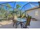 Screened patio with table and chairs, lush landscaping at 21228 Sandal Foot Dr, Venice, FL 34293