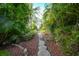 Stone pathway meandering through lush tropical landscape at 26266 Barcelos Ct, Punta Gorda, FL 33983