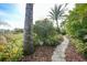 Landscaped backyard with stone pathway and palm trees at 26266 Barcelos Ct, Punta Gorda, FL 33983