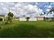 Large grassy backyard with a white vinyl fence, palm trees, and storage shed at 4064 Harbor Blvd, Port Charlotte, FL 33952