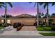 Tan house with three-car garage, landscaping, and palm trees at dusk at 4370 Turnberry Cir, North Port, FL 34288