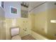 Outdated bathroom with yellow tile, bathtub, and toilet at 701 W Perry St, Englewood, FL 34223