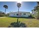 Charming ranch home with a pink door and lush lawn at 701 W Perry St, Englewood, FL 34223