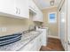 Bright laundry room with white cabinets, granite countertops, and modern washer/dryer at 9240 Pine Cove Dr, Englewood, FL 34224