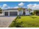 Modern two-car garage home with a lush lawn and paver driveway at 1169 Boundary Blvd, Rotonda West, FL 33947