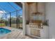 Outdoor kitchen with stainless steel grill,encased in a covered patio at 1169 Boundary Blvd, Rotonda West, FL 33947