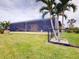 Large backyard with screened patio, lush landscaping, and a partially visible house at 170 Antilla Dr, Rotonda West, FL 33947