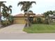 Tan one-story house with brown roof, palm trees, and landscaped yard at 170 Antilla Dr, Rotonda West, FL 33947