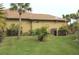 Backyard view of a tan house with palm trees, lush landscaping, and a well-maintained lawn at 170 Antilla Dr, Rotonda West, FL 33947