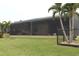 Backyard view of a house with a large screened patio, lush landscaping, and a fenced area at 170 Antilla Dr, Rotonda West, FL 33947