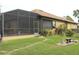 Backyard view of a tan house with a screened patio and a nicely landscaped yard at 170 Antilla Dr, Rotonda West, FL 33947