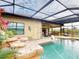 Inviting pool area with a covered patio, waterfall feature, and lush landscaping at 170 Antilla Dr, Rotonda West, FL 33947