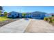 Front view of a light blue house with a large driveway at 221 E Wentworth St, Englewood, FL 34223