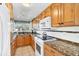 Kitchen with light wood cabinets, granite countertops and white appliances at 221 E Wentworth St, Englewood, FL 34223